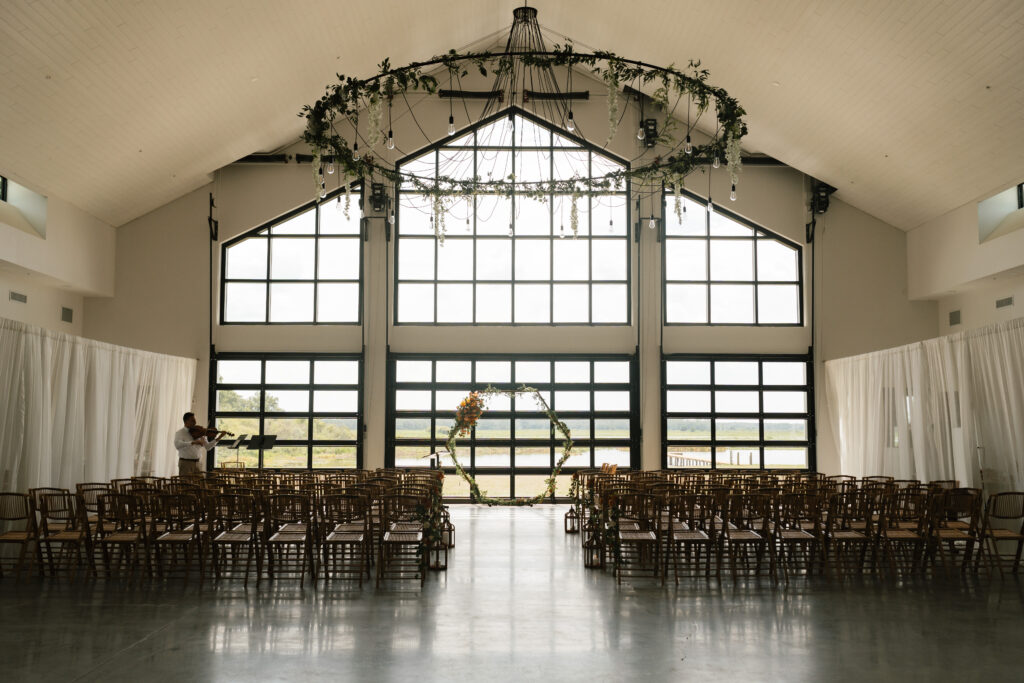 indoor wedding ceremony at barn wedding venue in Orlando, wedding floral on chandelier, wedding arch, ceremony set up
