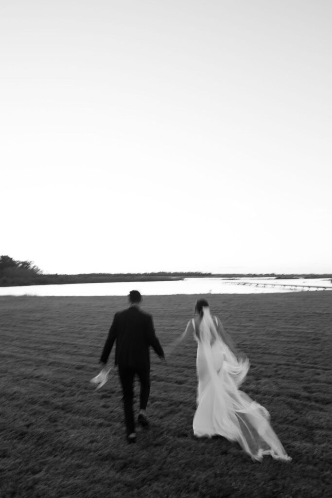 bride and groom walking on Central Florida farm towards the lakeside wedding venue photo location