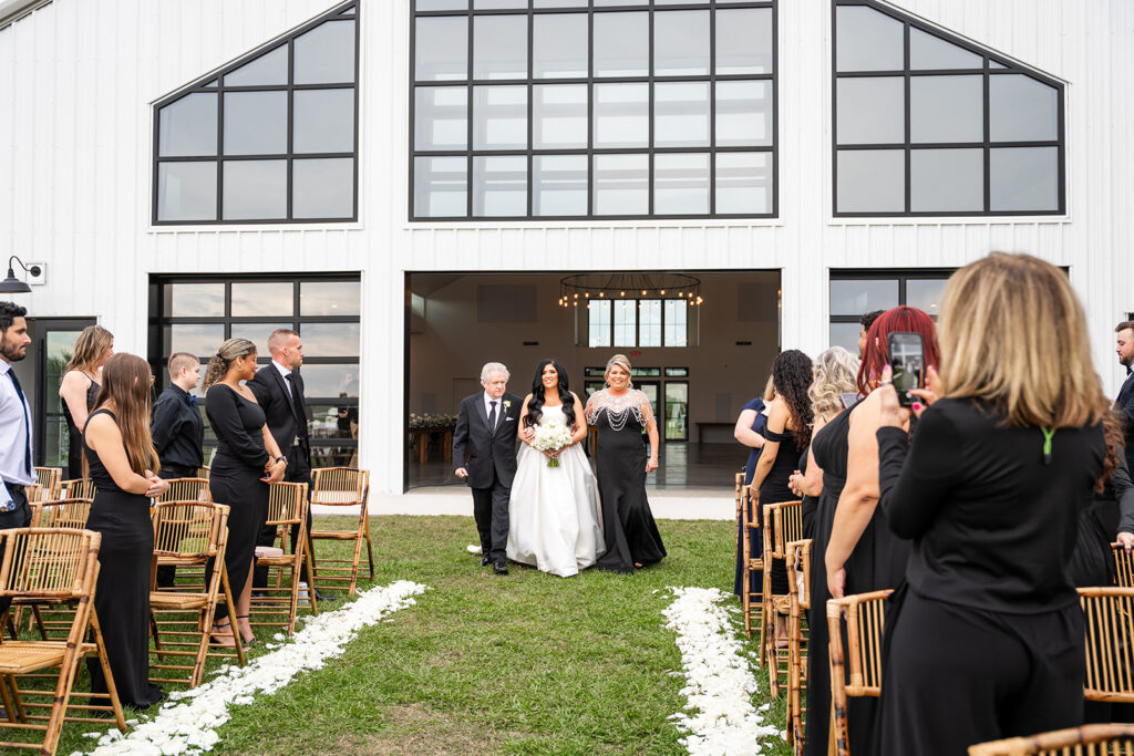 Bride walking with her parents for outdoor Florida ceremony, garage door grand entrance for bride