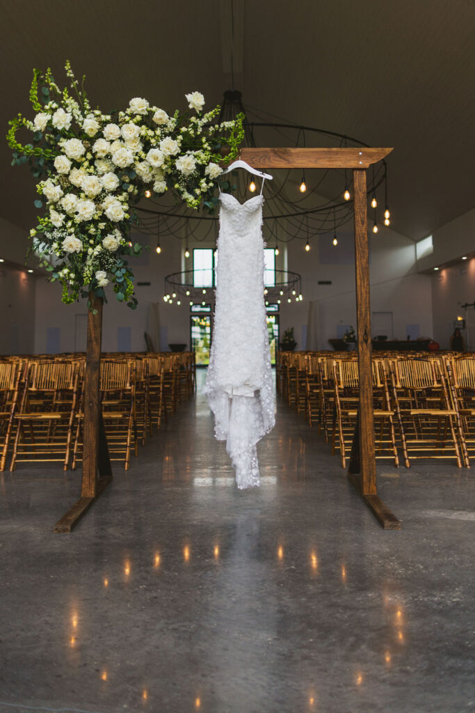wedding dress hanging on ceremonial arch at wedding venue in Florida,