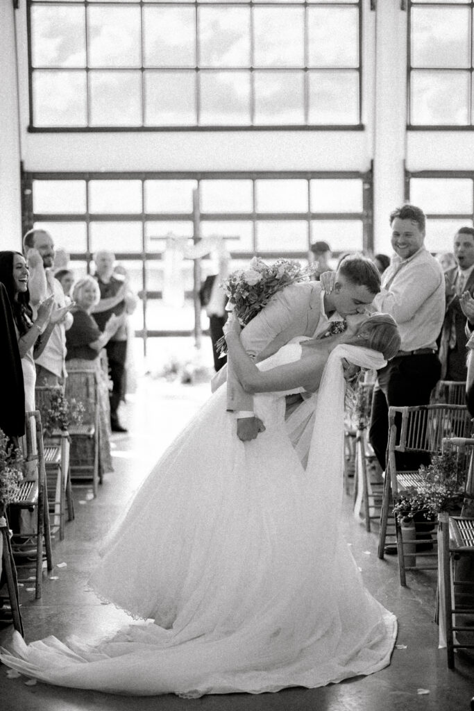 bride and groom dipping and kissing in the aisle after marriage ceremony at Lavender on the Lake, a lakeside wedding venue in Central Florida