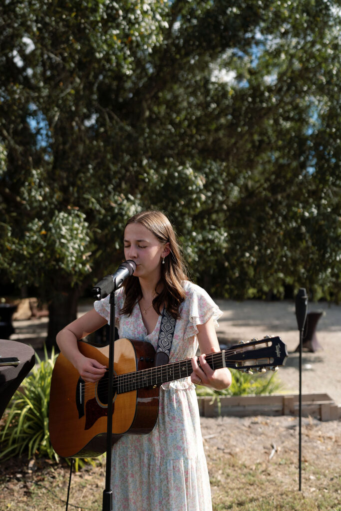 Girl playing a guitar for musical entertainment during cocktail hour at Central Florida wedding venue