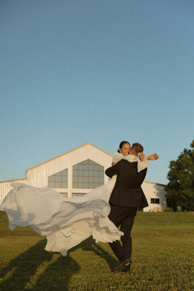 Groom is picking up and twirling his new bride at lakeside Florida venue