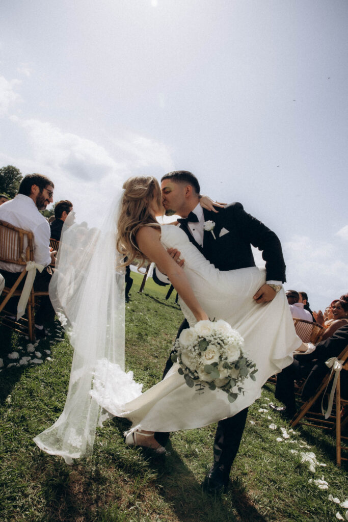 newlyweds post ceremony at Lavender on the Lake- a wedding venue in Central Florida - sharing a kiss in the aisle, dip and kiss