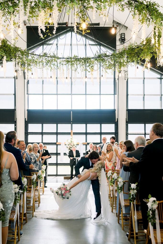 bride and groom sharing a kiss after indoor wedding ceremony at lakes side wedding venue