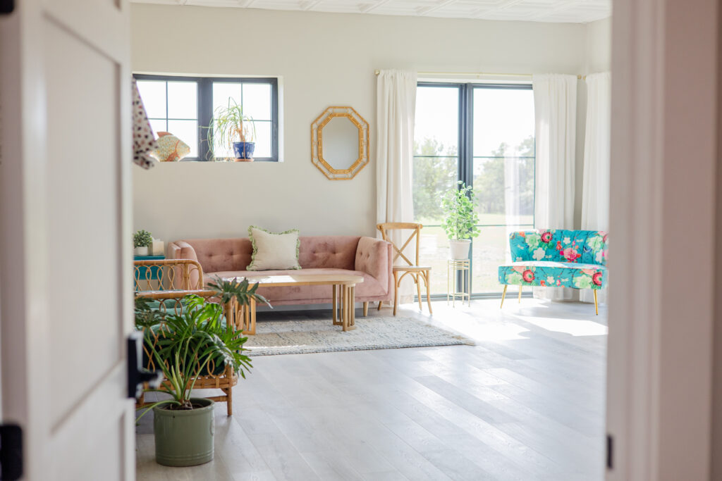 Door open to getting ready room with plants, daybed, pink couch, and a floral and butterfly sitting couch.