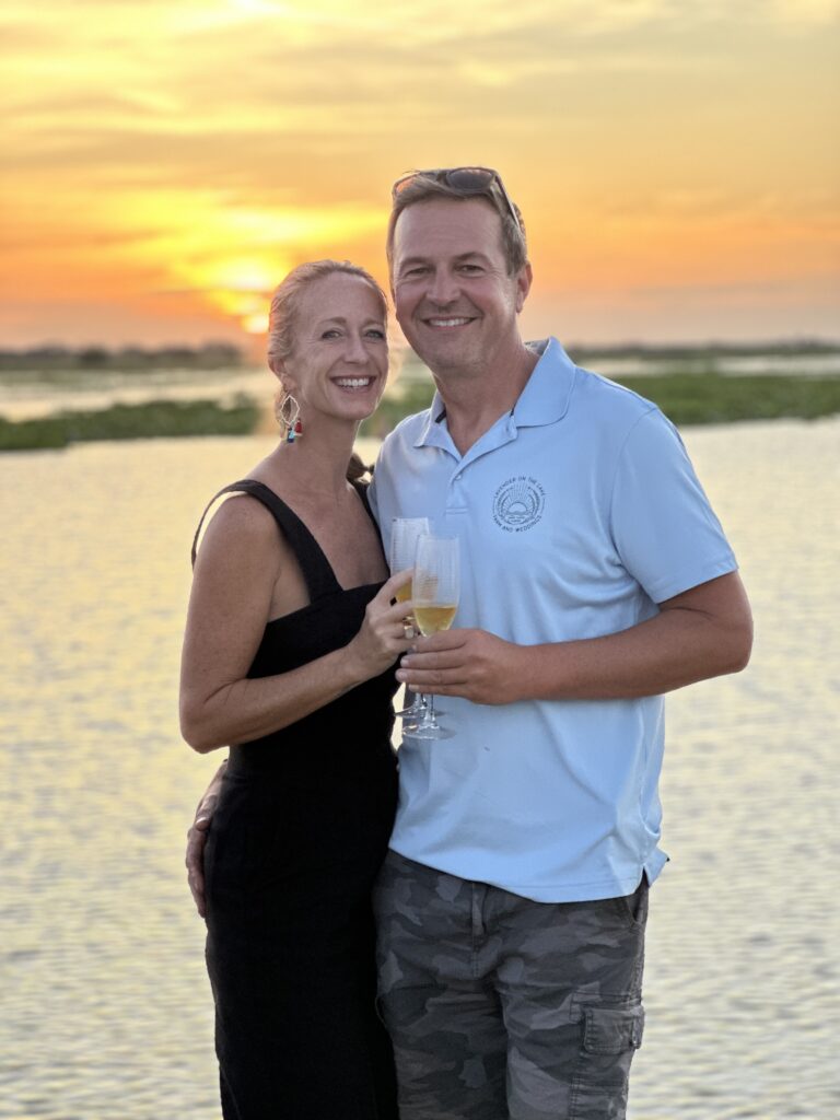 Man and woman standing lakeside with champagne