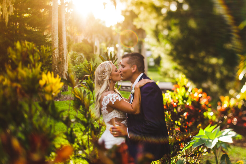 capturing a moment during golden hour, bride and groom kissing among the foliage in Orlando