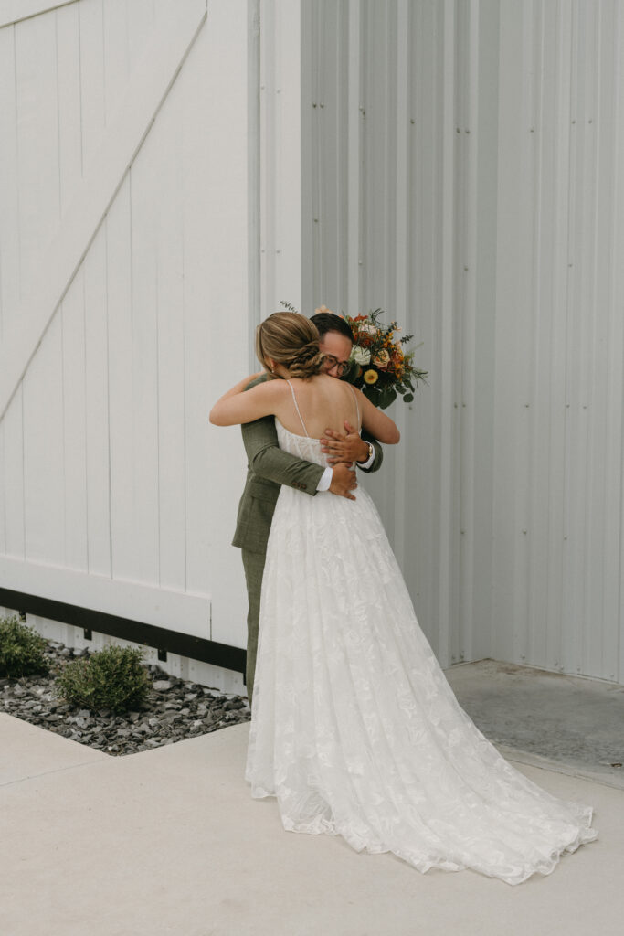 first look before wedding, floral bouquet, bride and groom, barn venue
