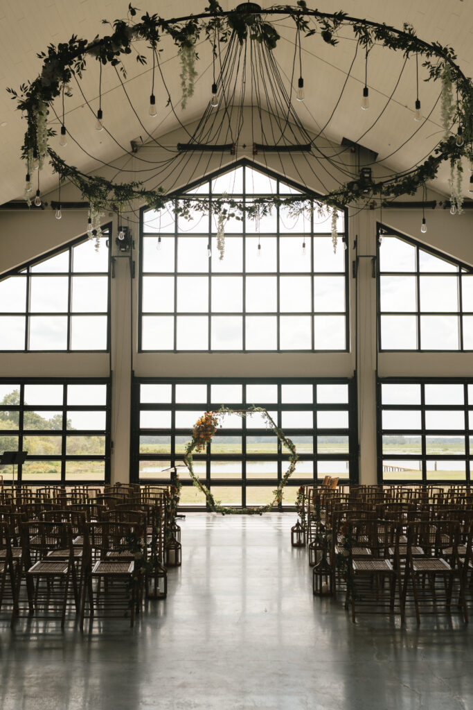 reception space for wedding, floral display on chandeliers, rental ceremonial arch with floral, guests watching wedding
